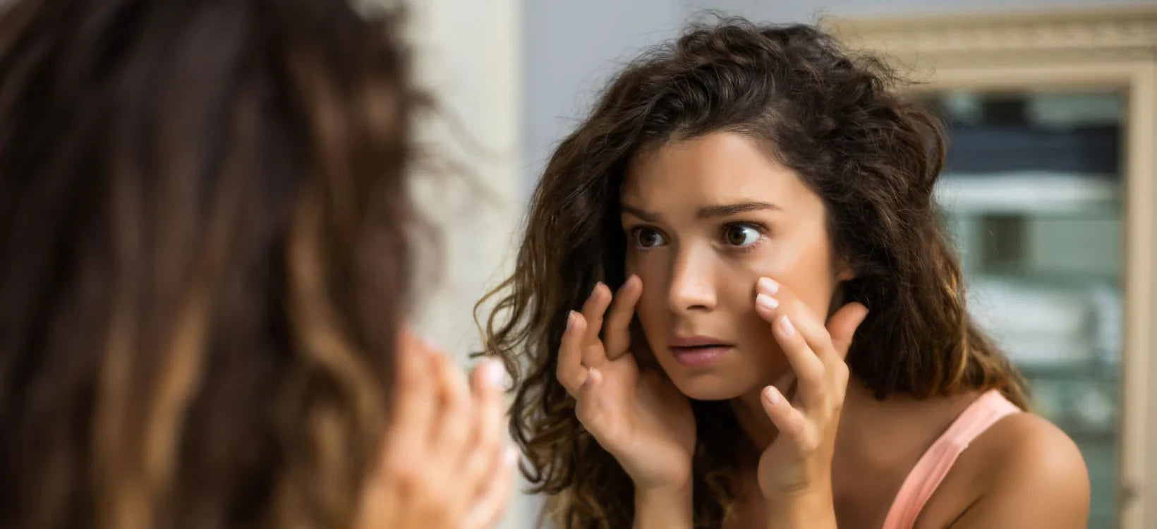 Woman examining her skin closely in the mirror.