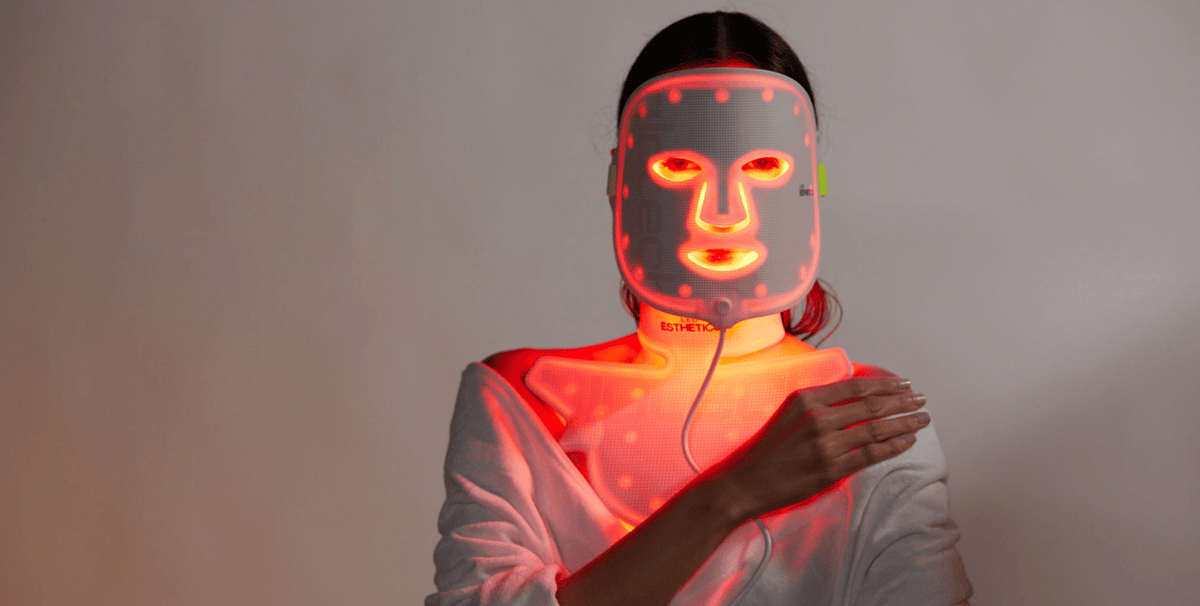 Woman using a red light therapy mask and neck device after microneedling to support skin recovery, reduce redness and boost collagen repair.