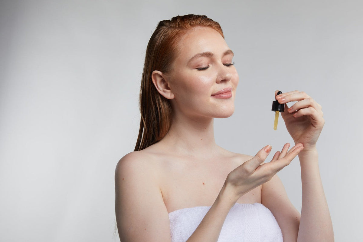 Woman applying facial serum before LED light therapy to support hydration, glow, and skin repair.