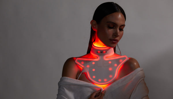 Woman using a red light therapy neck and chest device to support collagen production and reduce the appearance of stretch marks.