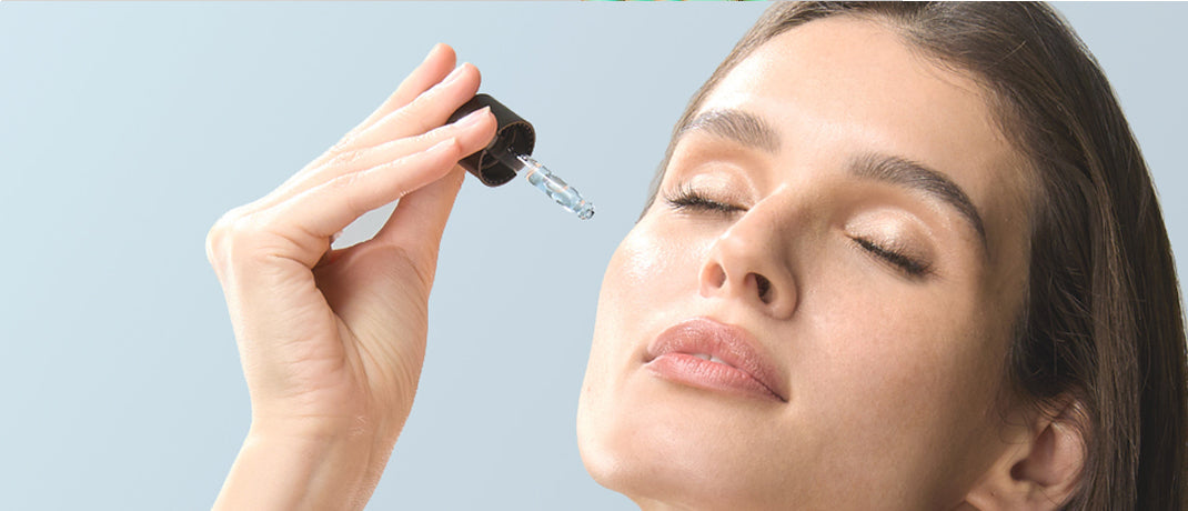 Woman applying hydrating facial serum with dropper to glowing skin, representing skincare routine for hormonal balance and radiant complexion.