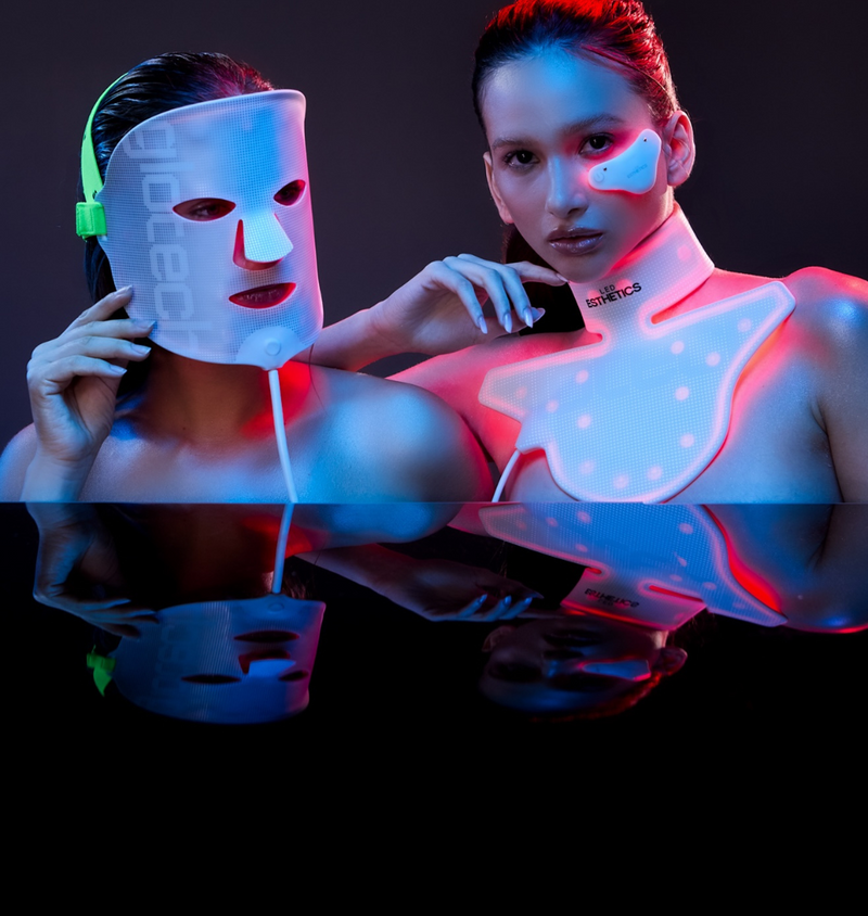 Two people wearing LED face masks with a dark background