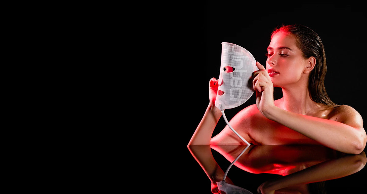Woman holding a white device with red lights on a black background